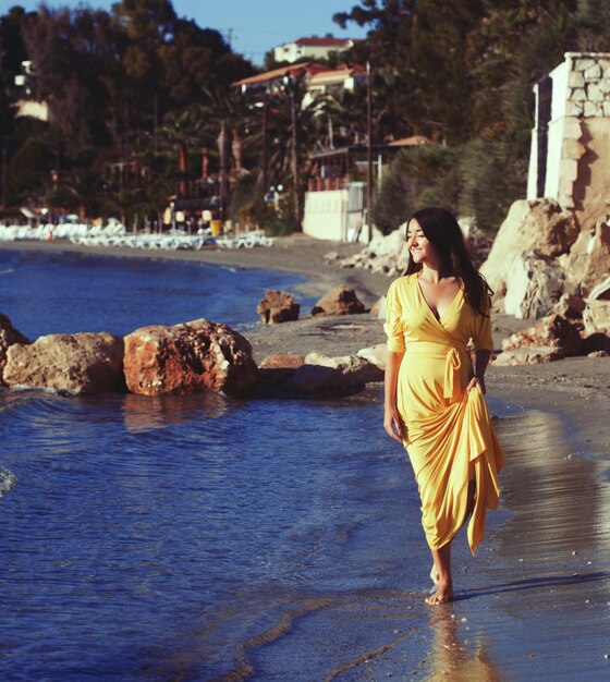 Femme avec une robe jaune sur une plage