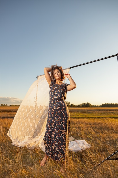 Femme en robe longue posant sur un champ