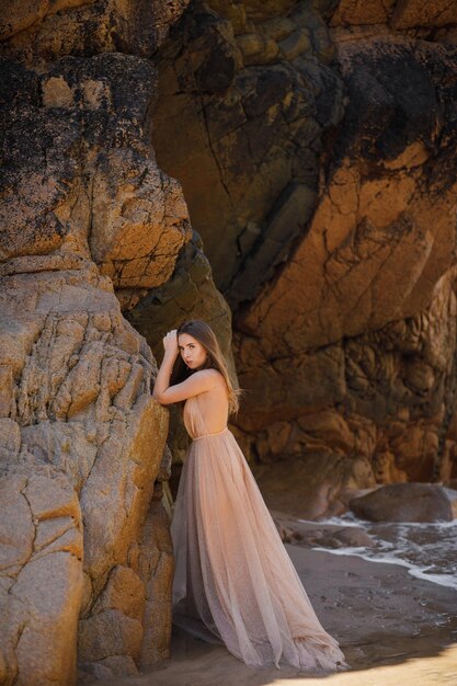 Femme en robe longue près des rochers et de l'océan