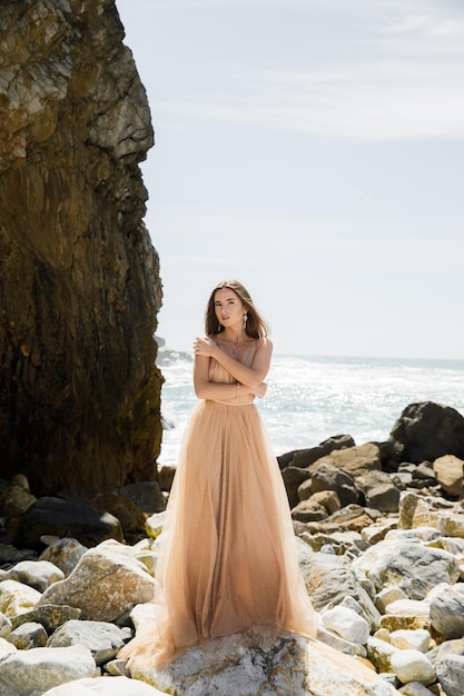 Femme en robe longue près des rochers et de l'océan