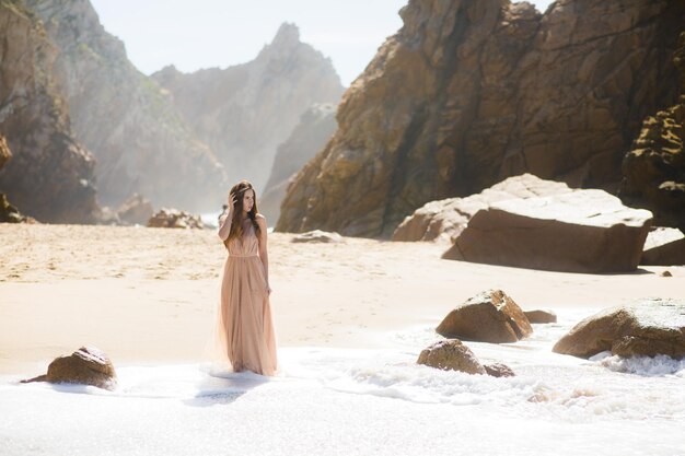 Femme en robe longue près des rochers et de l'océan