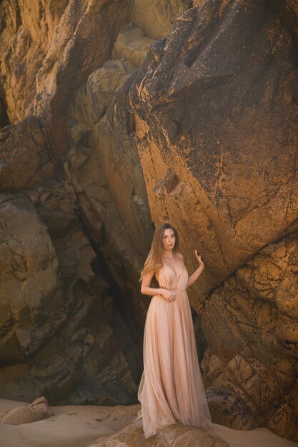 Femme en robe longue près des rochers et de l'océan