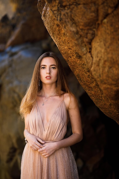 Femme en robe longue près des rochers et de l'océan