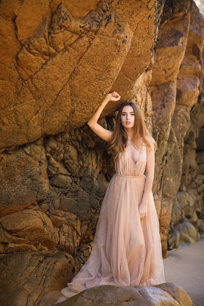 Femme en robe longue près des rochers et de l'océan