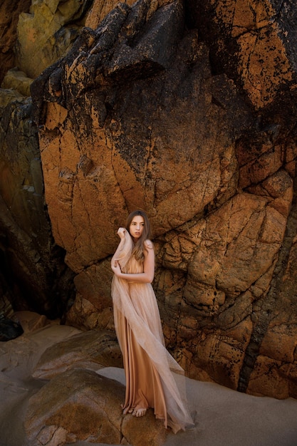 Femme en robe longue près des rochers et de l'océan