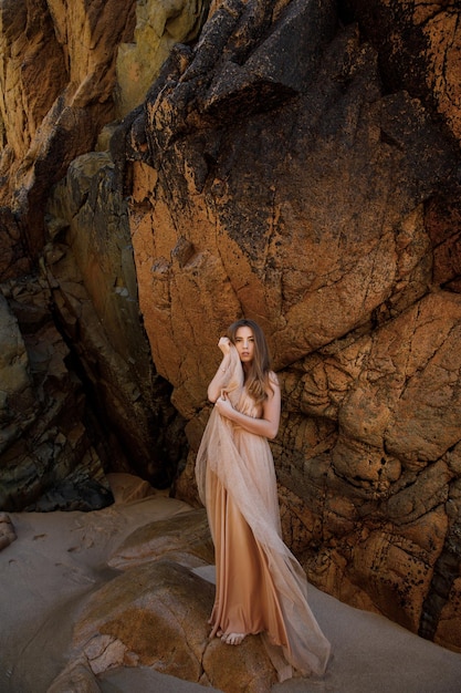 Femme en robe longue près des rochers et de l'océan