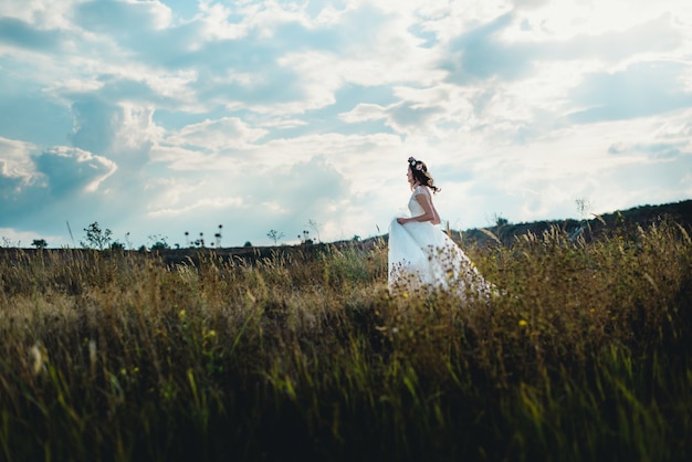 Femme avec robe de mariée marche sur une prairie