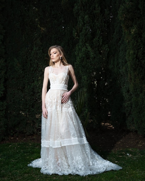 Une femme en robe de mariée se tient devant une forêt.