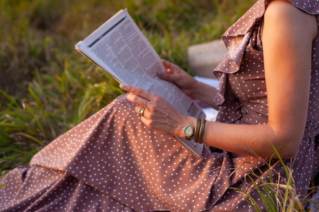 Une femme en robe marron est assise sur un pique-nique dans un parc avec vue panoramique