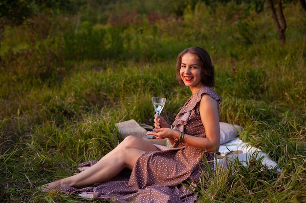 Une femme en robe marron est assise sur un pique-nique dans un parc avec vue panoramique