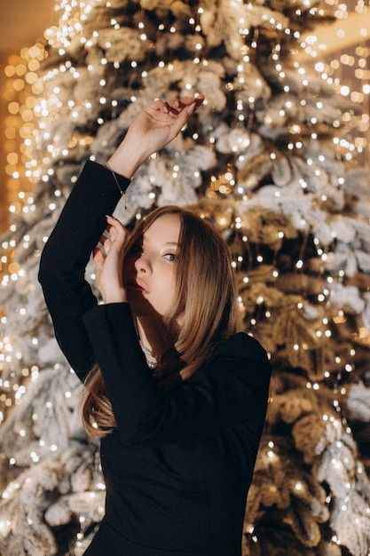 Femme en robe noire près de sapin de Noël