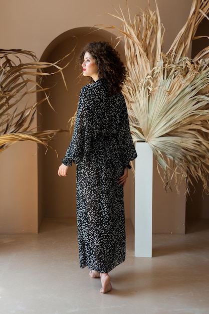 Une femme en robe noire se tient devant une plante