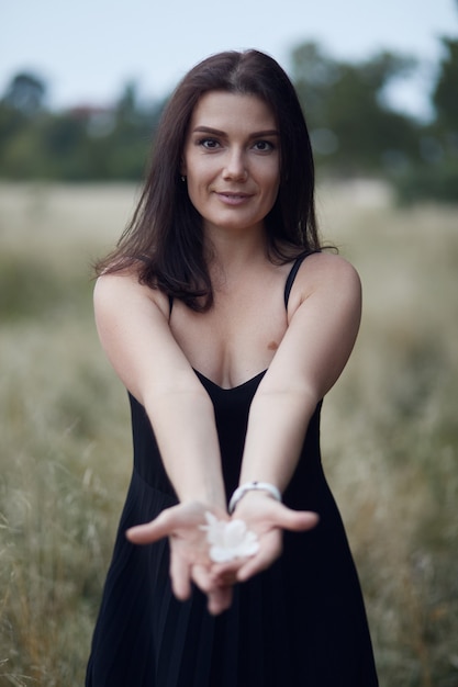 Femme en robe noire souriante sur la nature