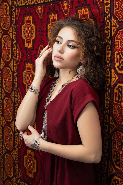 Femme en robe rouge avec des bijoux en argent sur fond d'ornement oriental