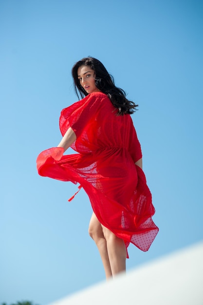 Une femme en robe rouge est debout sur un mur.