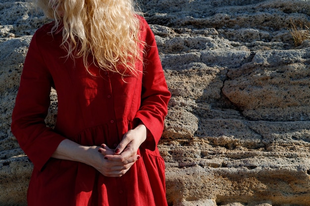 Une femme en robe rouge est debout sur la plage.