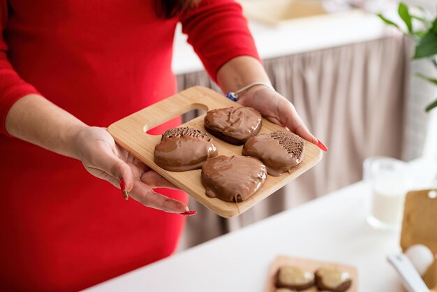 Photo une femme en robe rouge fait des biscuits de la saint-valentin dans la cuisine.