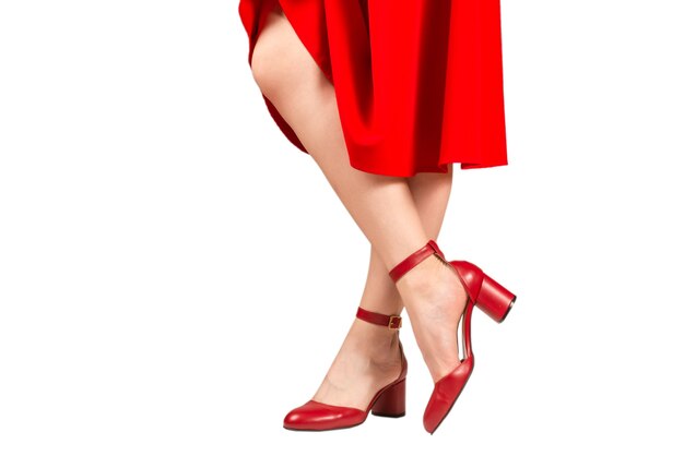 Femme en robe rouge et en sandales rouges rétro sur des talons isolés sur blanc.