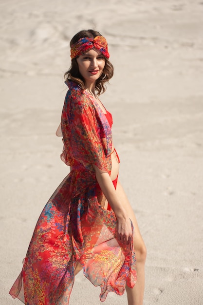 Une femme en robe rouge se promène sur la plage