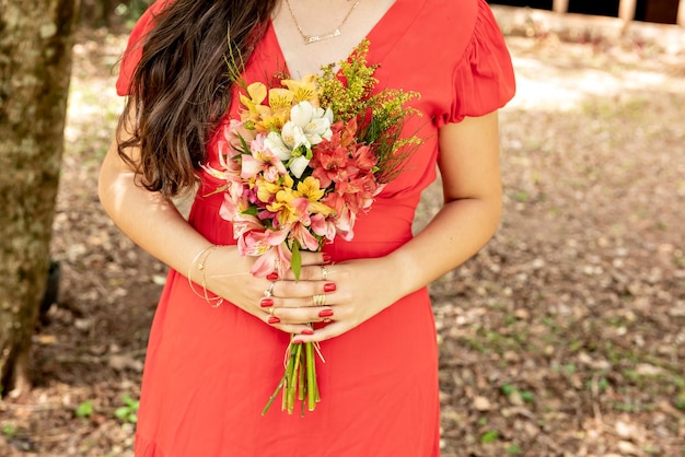 Femme en robe rouge tenant un bouquet de fleurs