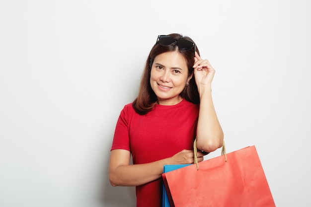 Femme en robe rouge tenant un sac en papier pour faire des emplettes