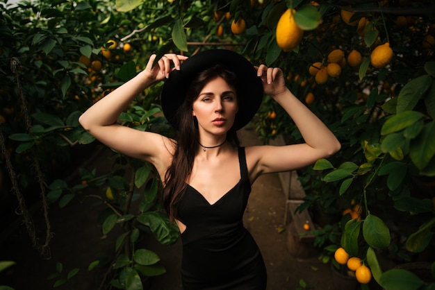 Femme en robe de soirée noire entourée d'orangers