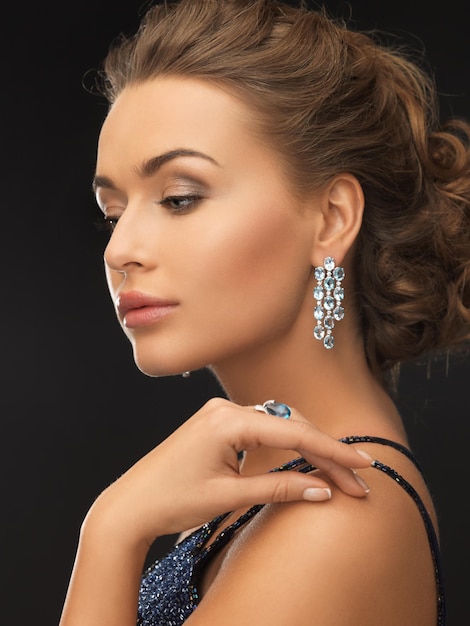 femme en robe de soirée portant des boucles d'oreilles et une bague en diamant