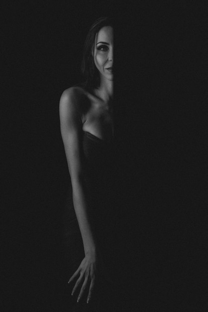 Femme en robe de soirée posant sur fond sombre