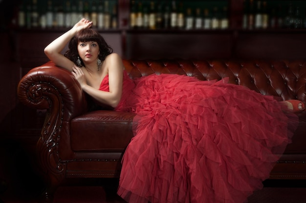 Femme en robe de soirée rouge allongée sur le canapé