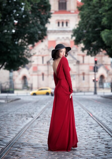 Femme en robe de soirée rouge posant dans la rue