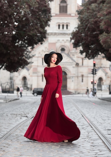 Femme en robe de soirée rouge posant dans la rue