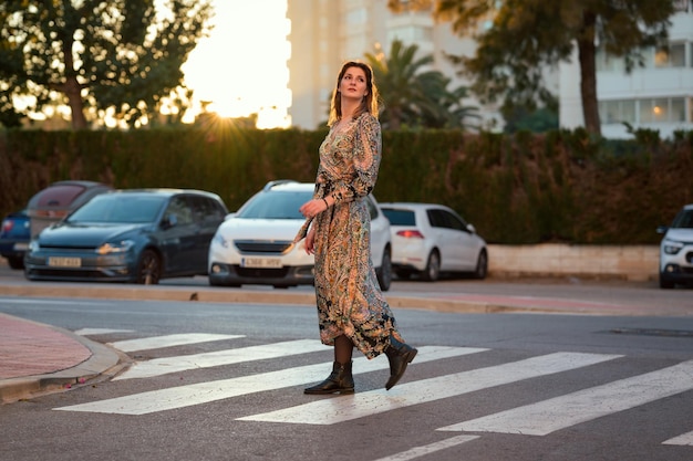 Une femme en robe traverse la rue
