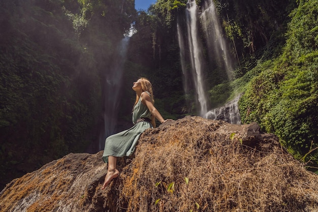 Femme en robe turquoise aux cascades de Sekumpul dans la jungle de l'île de Bali Indonésie Bali Travel Concept