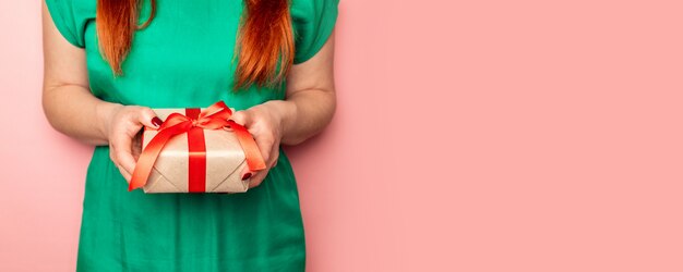 Femme en robe verte tient dans ses mains une boîte-cadeau de Noël