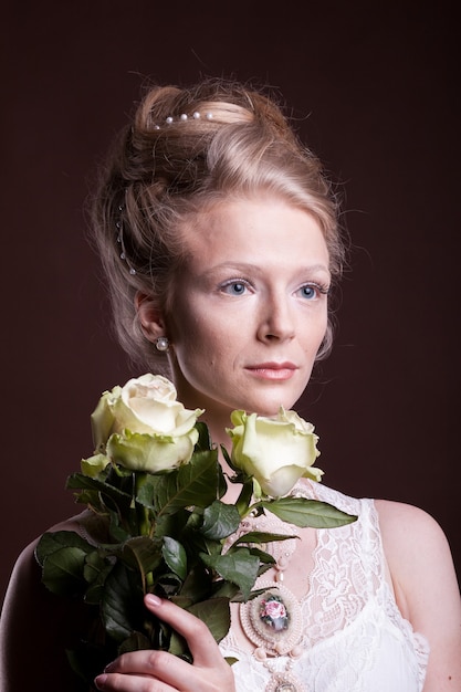 Femme en robe victorienne avec des roses en mains. Riche et vintage. Luxe et élégance. Studio photo