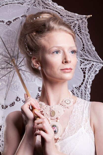 Femme en robe vintage tenant un parapluie en dentelle. Riche et vintage. Luxe et élégance. Studio photo