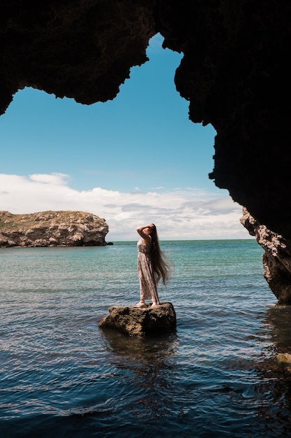 Une femme sur un rocher regardant au loin contre la mer