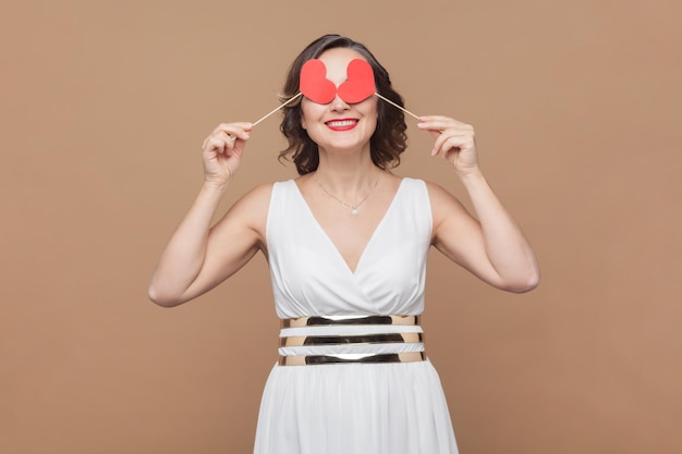 Femme romantique aux cheveux ondulés couvrant les yeux de petites oreilles rouges flirtant avec son petit ami