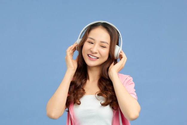 une femme romantique chante sur de la musique avec des écouteurs sur fond bleu