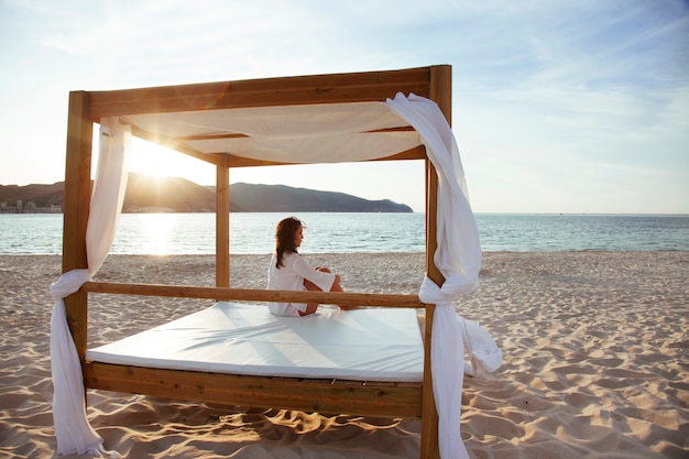 Femme romantique isolée sur un coucher de soleil tranquille sur la plage