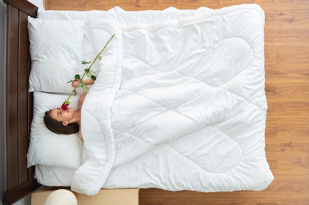 La Femme Avec Une Rose Allongée Sur Le Lit. Vue D'en-haut