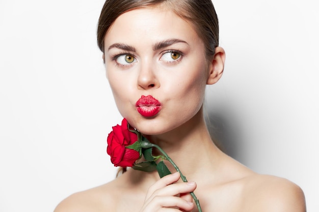 Photo une femme avec une rose dans les mains, des lèvres rouges, embrassant des épaules nues.