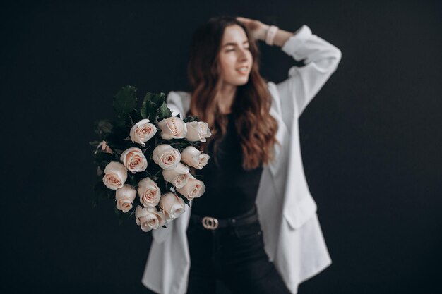 Femme avec des roses blanches sur fond noir