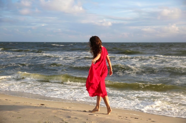 Femme en rouge sur la côte de la mer