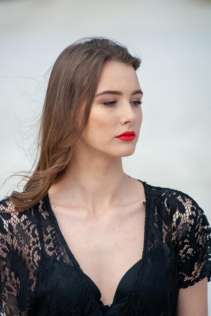 Une femme avec un rouge à lèvres rouge sur les lèvres regarde la caméra.