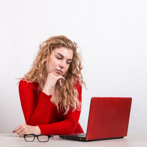 femme en rouge, travaillant à distance à l'ordinateur sur blanc.