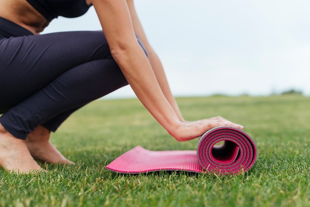 Photo femme roulant tapis de yoga en plein air