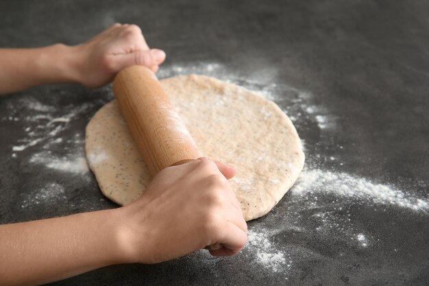 Femme rouler la pâte avec des graines de pavot sur le gros plan de table