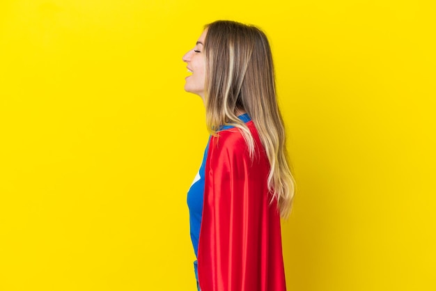 Femme roumaine de super héros isolée sur fond jaune riant en position latérale