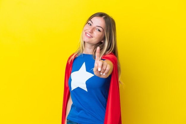 Femme roumaine de super héros d'isolement sur le fond jaune montrant et soulevant un doigt